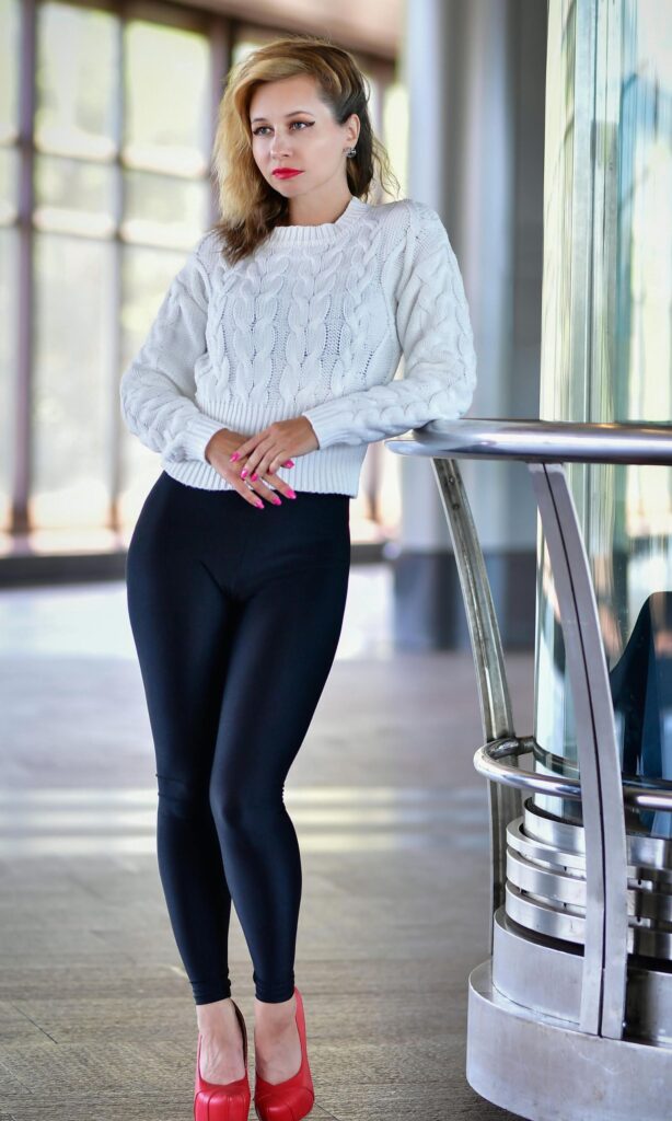Stylish woman wearing layered fall outfit with camel coat, white sweater, dark jeans and ankle boots - perfect for casual everyday looks.